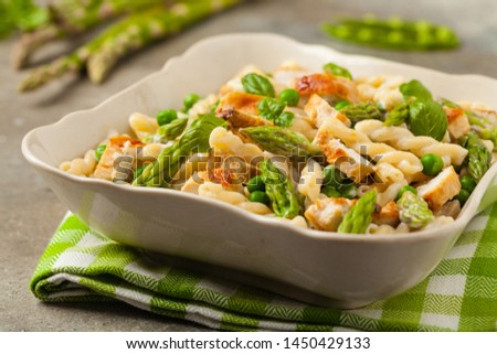 Italian pasta fusilli. Salad with chicken and asparagus in Béchamel sauce. Best eaten hot. Stone background. Front view. 