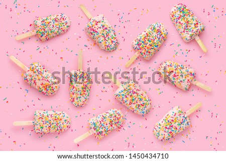 creative concept of festive background with popsicles, sprinkles and icing over pink background