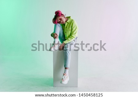 woman with pink hair sits on a neon cube
