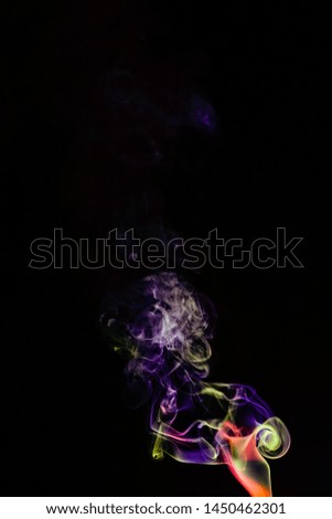 Multicolored smoke in the air is an abstract shape on a black background.