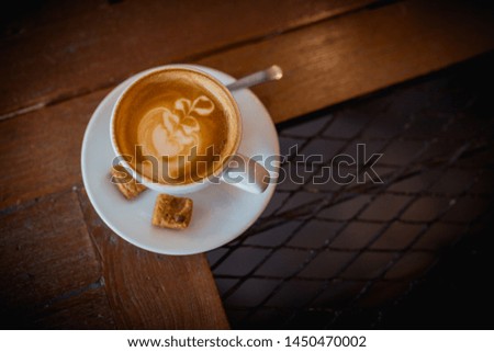 Picture of latte hot coffee with foam milk art on a wooden table