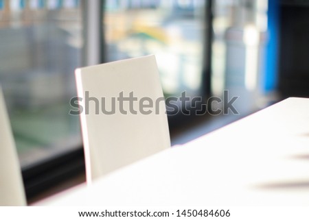 Abstract image with very shallow depth of field, showing a white chair in focus with some lovely blur and bokeh behind.