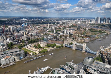 Aerial view of the muddy River Thames with Tower of London Castle, Tower Bridge, City Hall and Canary Wharf skyscrapers London England