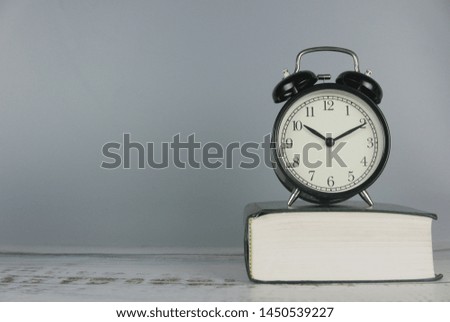 Clock over book. Time and education concept. Copy space for text or logo.