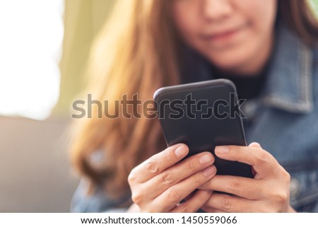 Closeup image of a beautiful asian woman holding , using and looking at smart phone