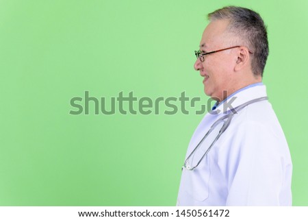 Profile view of happy mature Japanese man doctor smiling