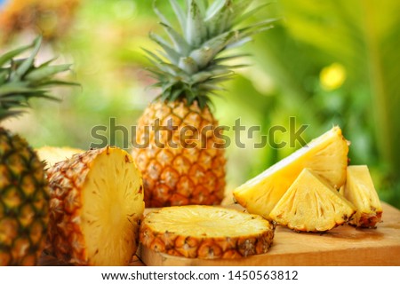 Sliced and whole of Pineapple(Ananas comosus) on wooden table with blurred 
 garden background.Sweet,sour and juicy taste.Have a lot of fiber,vitamins C and minerals.Food,Fruits or healthcare concept. Royalty-Free Stock Photo #1450563812