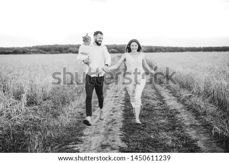 happy family on the walk in the wheat field: stylish bearded man and a cute young wife with her little daughter happy parents with her baby.  black and white