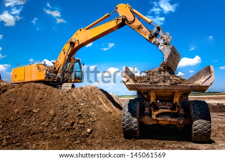 Excavator loading dumper truck tipper in sandpit in highway construction site Royalty-Free Stock Photo #145061569