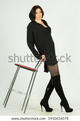 Girl in a black shirt with a bar stool. On a gray background.