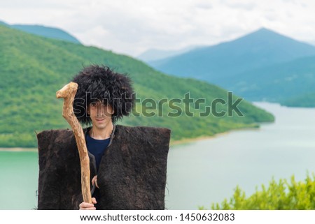 Georgian man in a beech costume on a background of mountains. Selective focus.