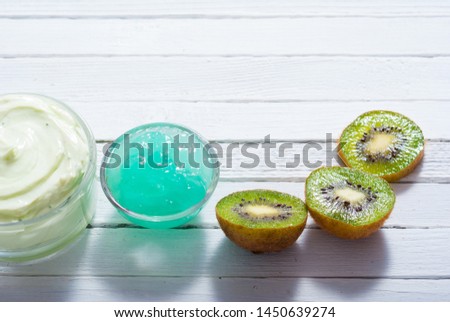 moisturizer and anti aging gel with kiwi on white wooden table
