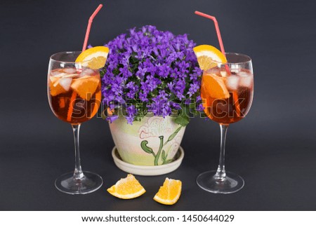 Refreshing aperol spritz cocktail with ice and orange slices, on a black background