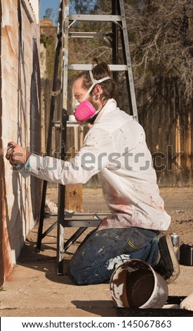 Adult graffiti artist working on mural outdoors Royalty-Free Stock Photo #145067863