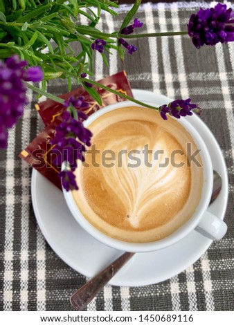 White cappuccino cup with sugar on checkered tablecloth and lavender pot