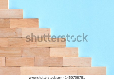 Brown wooden blocks stairs shape idea on blue background composition. Flat lay and top view photo