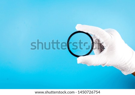 white gloved hand holding a camera lens. Top view, Professional photo camera repair.
