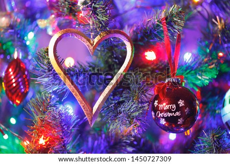 Christmas tree with heart shape decoration and purple illumination, close-up view