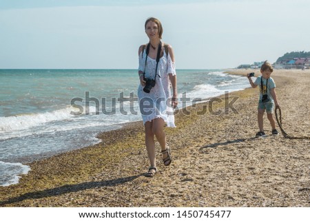 Mom and son with cameras on the beach, ocean. Joint occupation of mother and child to take photos. Interaction in the family, common interests.