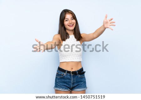 Young woman over isolated blue background presenting and inviting to come with hand
