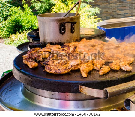 chicken cooking on a griddle for hot meals at a farmers market 
