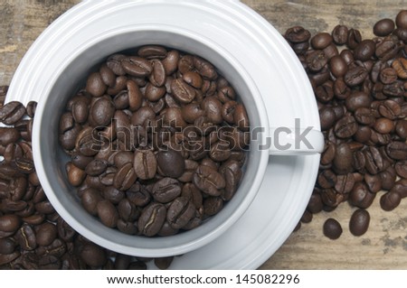 Roasted coffee beans with white cup on wood table. bird view close up
