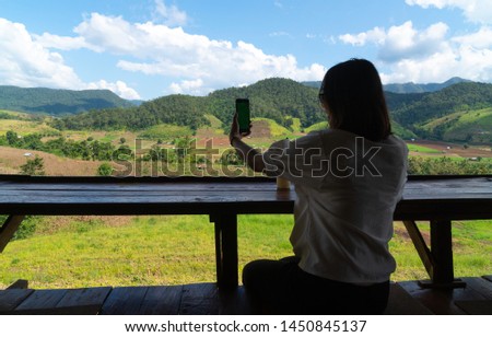 Silhouette woman using smart phone. Background mountain and forest in summer season.