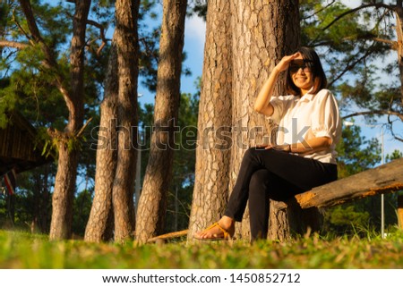 Woman sitting on a timber in park. relax and happy in sunset.