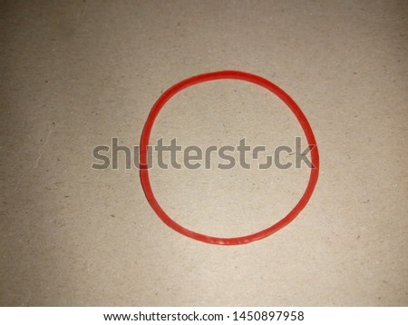Red rubber band on Light brown background  Royalty-Free Stock Photo #1450897958