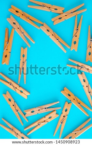 Wooden yellow clothespins are scattered on a cyan-blue background. Frame of clothespins. View from above. Copy space. Flat lay. The concept is natural, eco-friendly