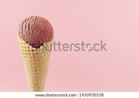 Chocolate brown creamy ice cream in crisp waffle cone on pastel pink background, closeup, details, top, half.