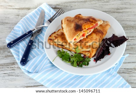Pizza calzones on plate on napkin on wooden table