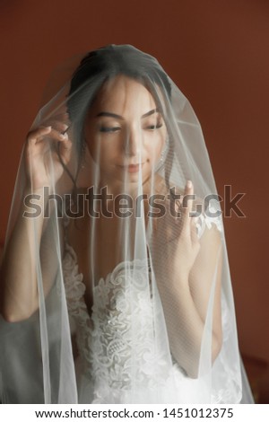 girl in a wedding dress at home; preparing the bride for the holiday; 
bride in a wedding dress against a dark wall

