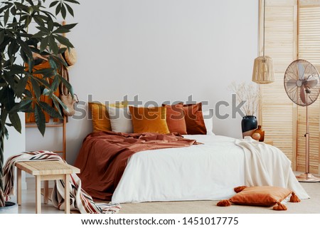 Autumn colored pillows on king size bed in chic bedroom interior
