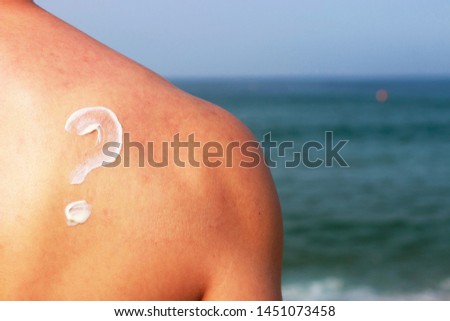 Question mark drawn by sunscreen on a male back, skin protection concept