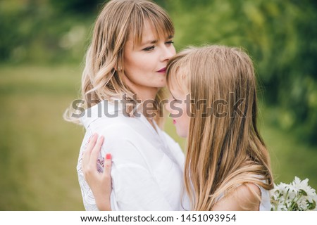happy mother's day! child daughter congratulates mother and gives a bouquet of chamomile flowers. Blondie mom and dauther together. 