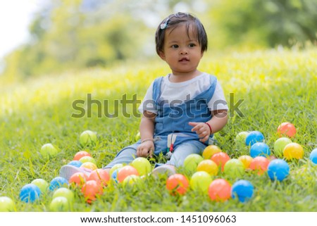 Happy small child and colored balls in the park