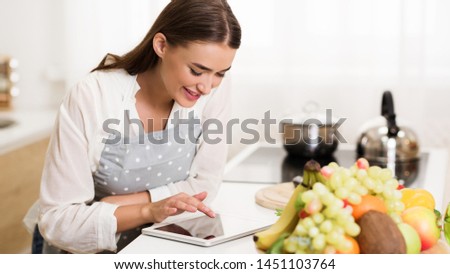 Millennial woman searching recipe on tablet, choosing what to cook for dinner
