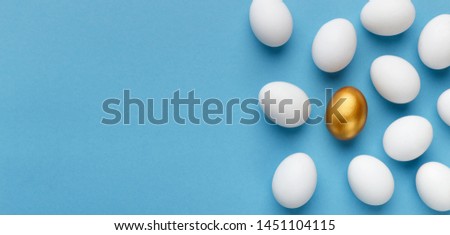 Concept of individuality, diversity and being unique. One golden egg in crowd of white ones, blue panorama background with empty space