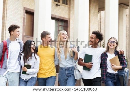 Cheerful college students walking together after study, resting in campus Royalty-Free Stock Photo #1451108060