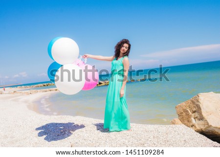 Beautiful girl on the beach with colorful balloons in summer
