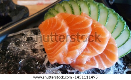 Fresh salmon fillets are in the ice in a black dish.