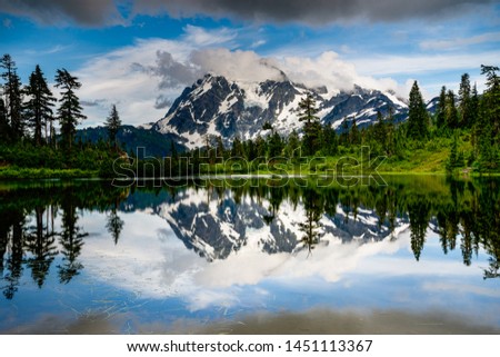 beautiful reflection of mountain and awesome clouds on the sky with forest