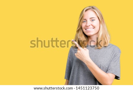 Beautiful young woman wearing oversize casual t-shirt over isolated background cheerful with a smile of face pointing with hand and finger up to the side with happy and natural expression on face