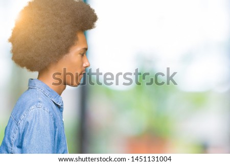 Young african american man with afro hair looking to side, relax profile pose with natural face with confident smile.