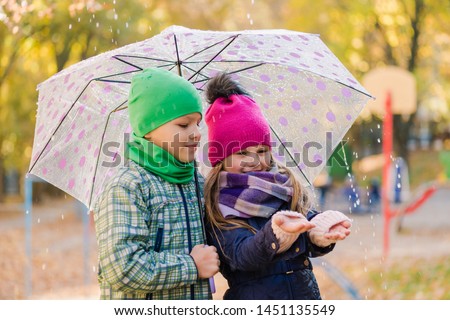 Romantic preteen kids during rain under umbrella