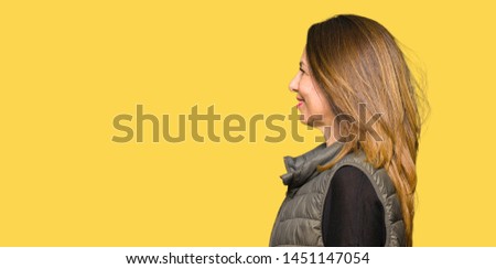 Beautiful middle age woman wearing winter vest looking to side, relax profile pose with natural face with confident smile.