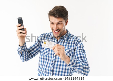 Photo of happy man in casual shirt holding credit card and smartphone isolated over white background