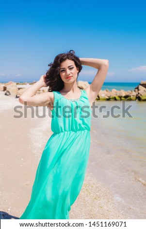 Young beautiful girl in a long dress on the beach in summer
