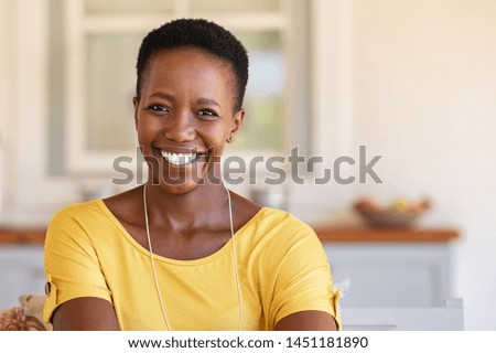Mature happy woman smiling and looking at camera. Portrait of african american woman in casual clothing and curly short hair relaxing at home.  Portrait of successful black lady with copy space. Royalty-Free Stock Photo #1451181890